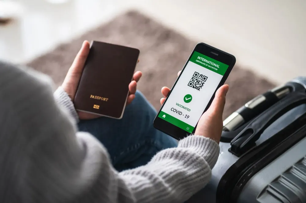 Woman holding her passport and her phone, showing a digital vaccine passport